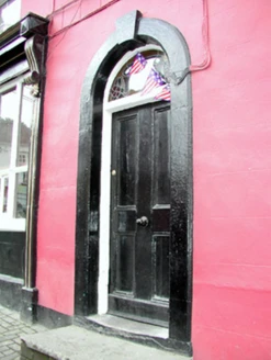 The arched doorway of Conway's Corner House with fanlight window and deep pink walls