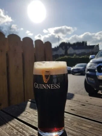 A pint of Guinness on a table in the beer garden at Conway's Corner House on a sunny day