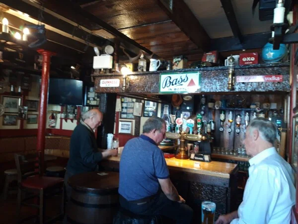 Inside the bar at Conway's Corner House with patrons, vintage Bass sign and traditional decor